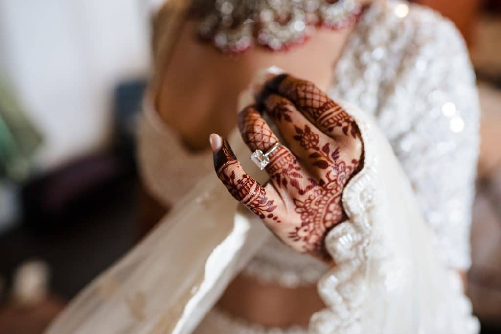 Indian-Wedding-in-Maui-_0003 - Ann Arbor Wedding Photographer Close-up of a bride's hands with intricate henna designs and a diamond ring, held together in a prayer-like pose.