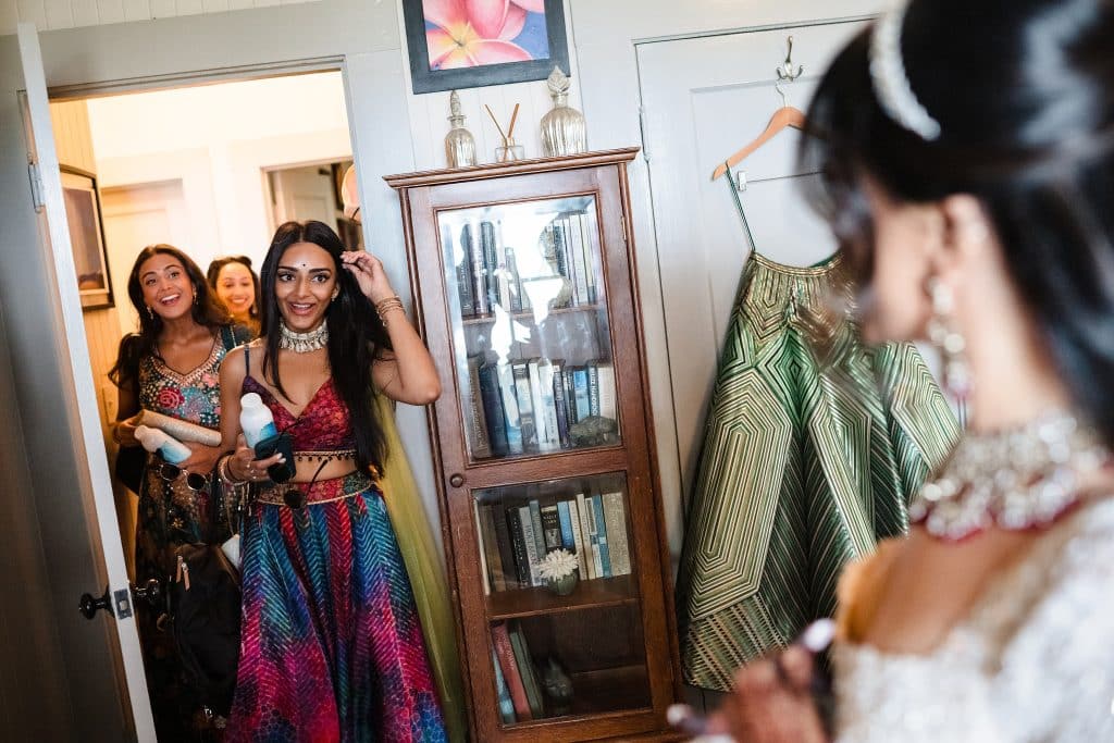 Indian-Wedding-in-Maui-_0004 - Ann Arbor Wedding Photographer Frieds and family of the bride entering the room as she's getting ready and smiling at her.