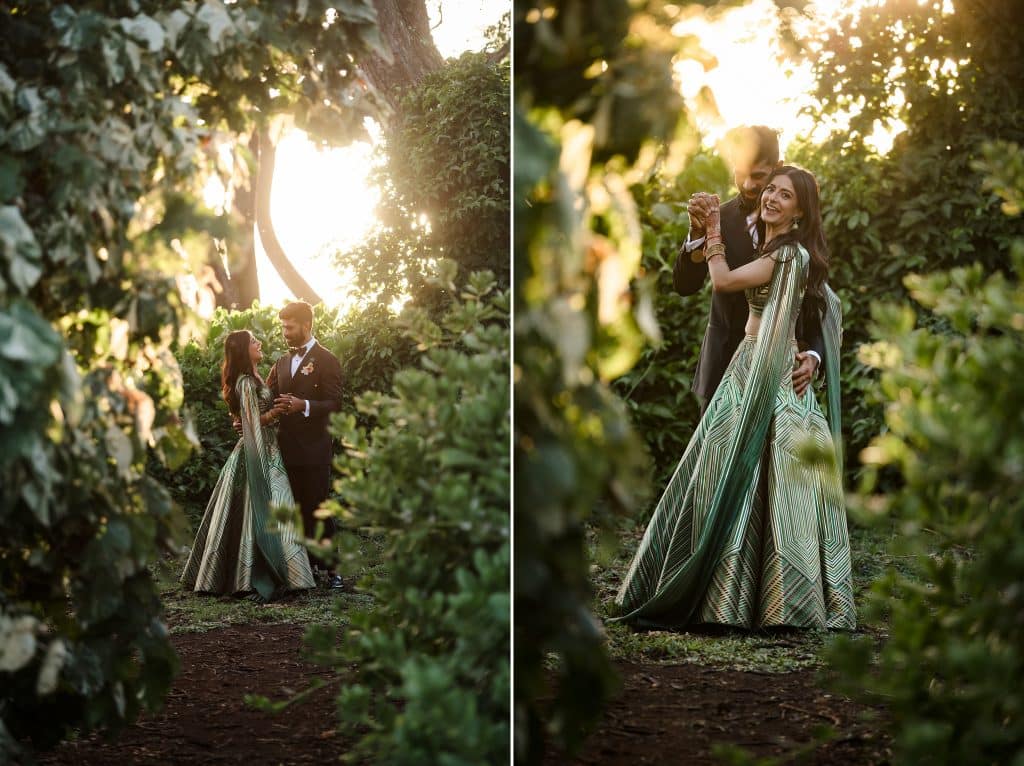 Indian-Wedding-in-Maui-_0037 - Ann Arbor Wedding Photographer Couple holding hands and smiling while the sun sets behind them. They're surrounded by lush greenery.